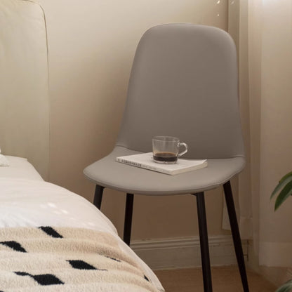 Gray chair with a cup of coffee and book on a bed in a bedroom setting