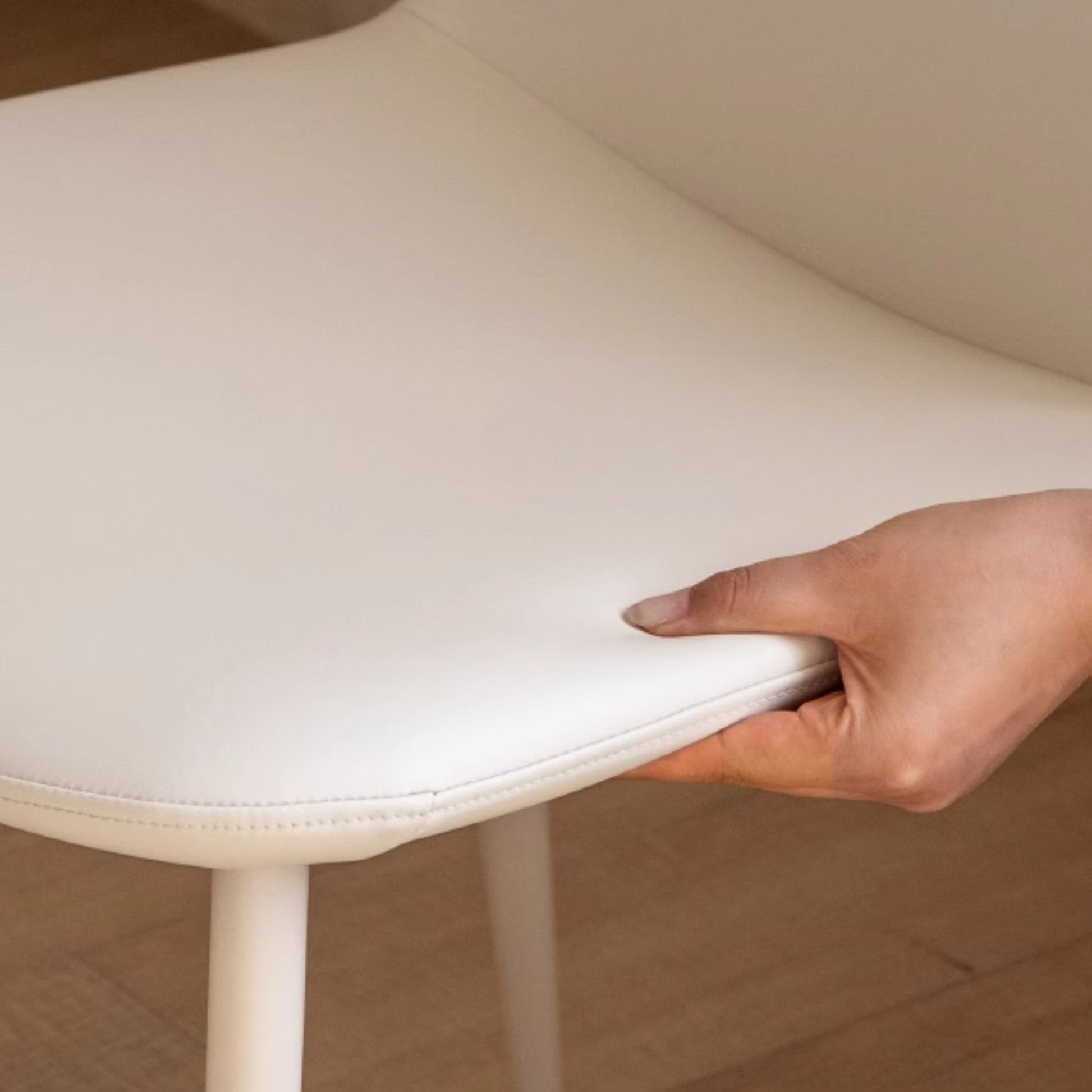 Hand holding a white chair with a neutral background