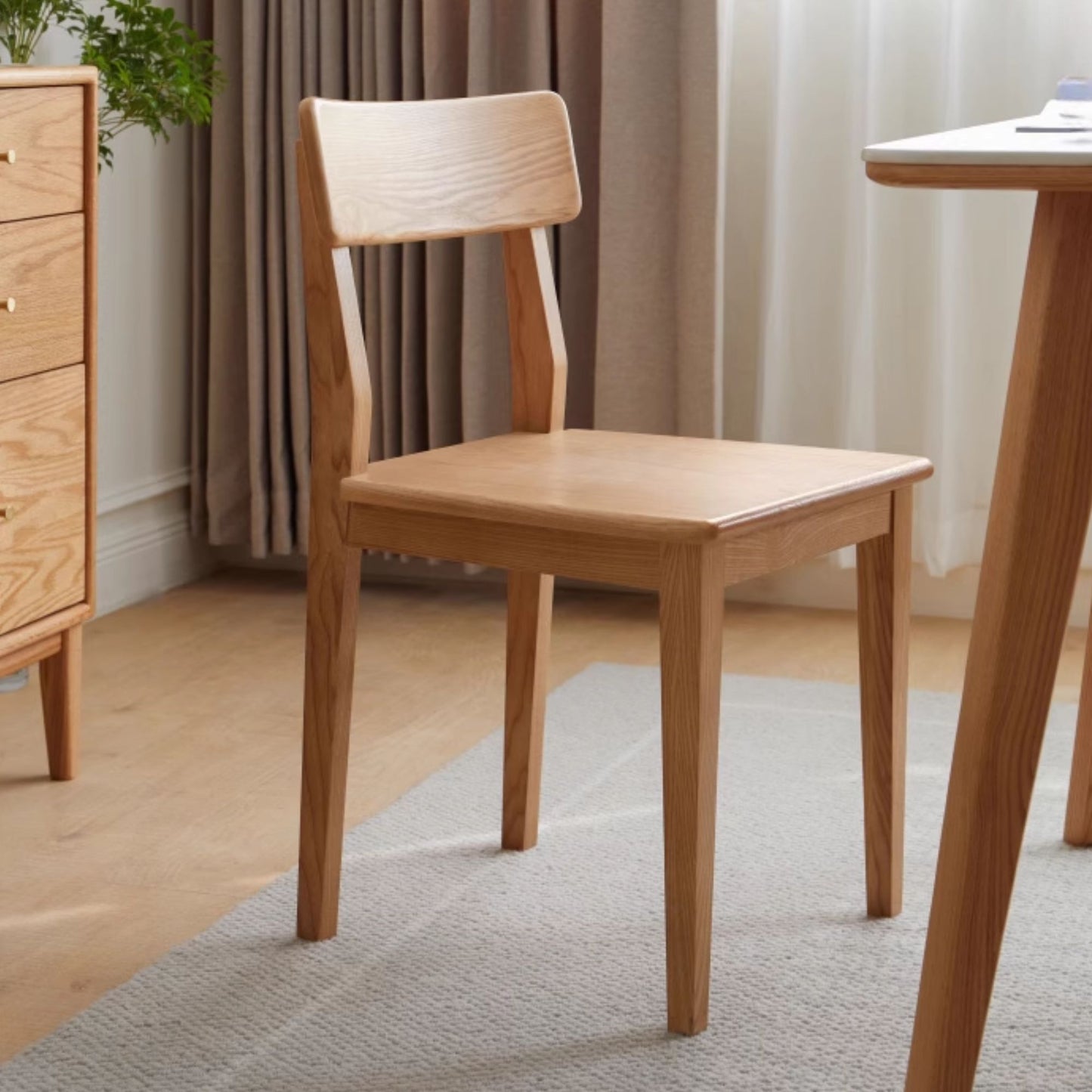 Wooden chair in a room with curtains and a table.