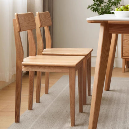 Wooden dining table and chairs in a room with a neutral color scheme.