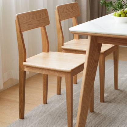 Wooden dining table and chairs in a room with light-colored walls and flooring.