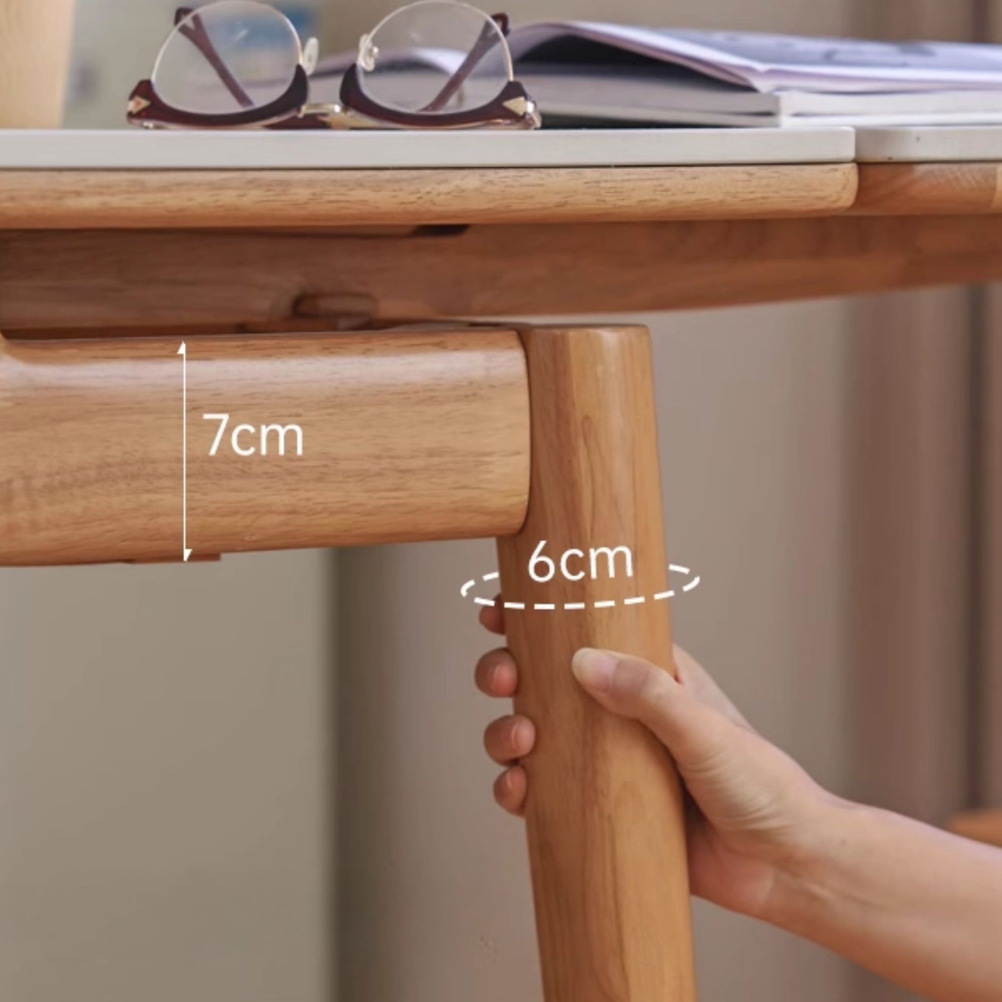 Wooden table leg with measurements and a hand holding it
