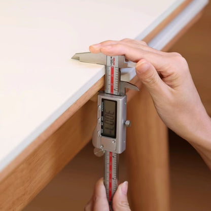 Digital caliper being used to measure a wooden surface