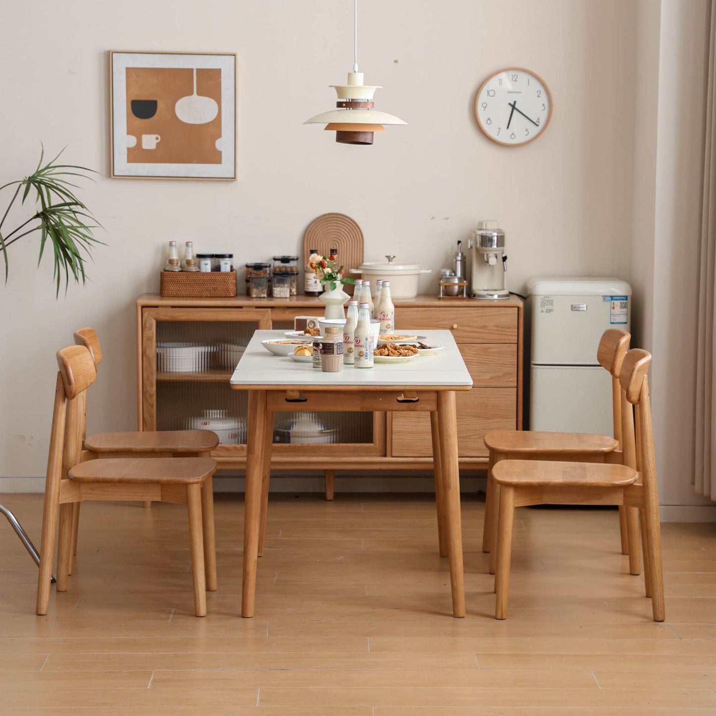 Dining area with wooden table and chairs in a room with a clock on the wall.